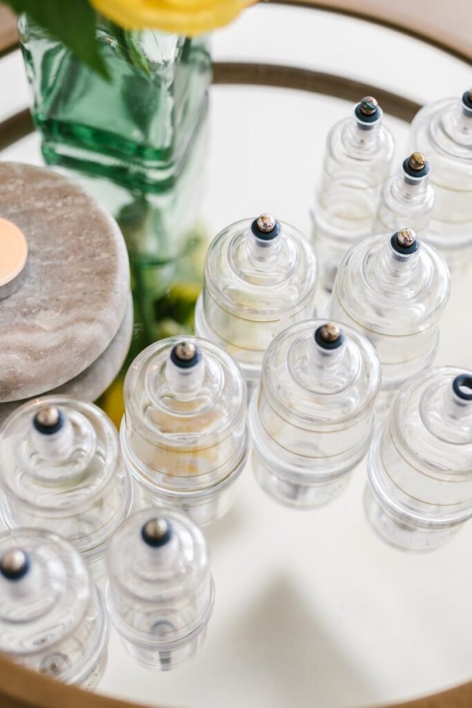 pexels-photo-8312798-8312798 A stylish arrangement of glass cupping jars on a mirrored table with a candle and flowers, ideal for spa settings.